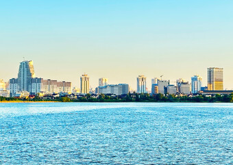 City near lake at sunset. Downtown Minsk and Lake Drozdy. Long Panoramic River Downtown City Skyline. Panarama of City with buildings and  houses on waterfront. buildings and downtown city skyline