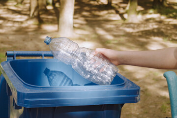 children clean up the forest by throwing empty bottles into a bag and a trash can