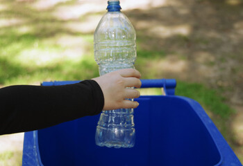 children clean up the forest by throwing empty bottles into a bag and a trash can