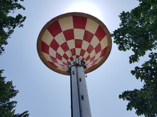 A view of a water tower in a park with blue sky.