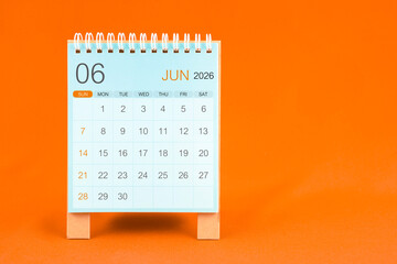 June 2026 desk calendar stand on orange color textile background.