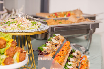 A colorful and delicious buffet spread featuring a wide variety of international dishes, including fizzy cola, lemon tart, creamy cheesecake, blueberry tart, crispy fried chicken, and savory pasta