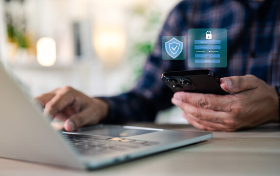 Hand of a man using mobile phone and laptop, secure access to user personal information, secure Internet access, information security encryption. Cybersecurity internet network data privacy concepts.