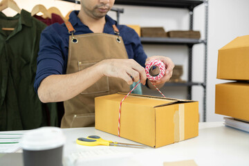 A man is packing things into boxes. He uses scotch tape and string to tie the boxes, writes...