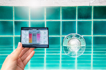 Water tester test kit in girl hand over swimming pool light install on the wall, pool light illumination, quality water tester