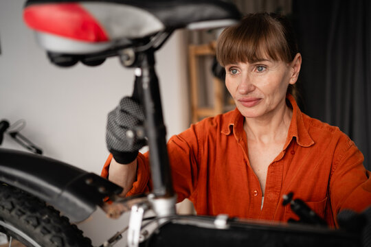 Portrait of concentrated female mechanic repairing bicycle at home in room.