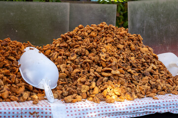 A large heap of crispy pork cracklings displayed on a market stall.