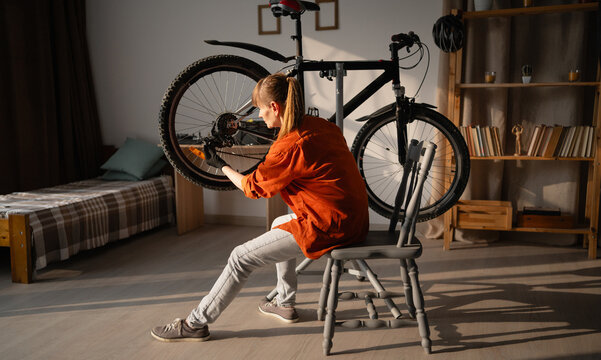 middle aged lady repairing a bicycle at home. Female cyclist adjusting bike rear derailleur with specialized equipment