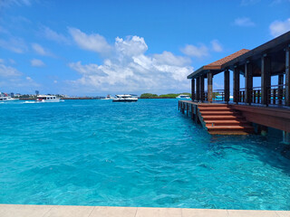 Crystal-clear turquoise waters extend from a wooden pier with stairs leading into the sea,...