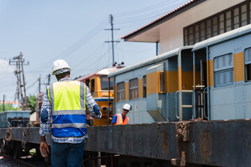 Railway Engineer Inspecting Train Cars at a Station, Back View of Worker in Safety Vest at Rail Depot, Industrial Worker Supervising Operations in a Train Yard