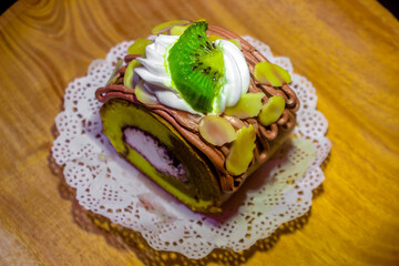 Indonesian sweet cakes served on natural wooden plate and spoon with black background highlighting traditional dessert texture and authentic tropical food style