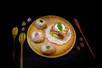 Indonesian sweet cakes served on natural wooden plate and spoon with black background highlighting...