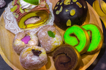 Indonesian sweet cakes served on natural wooden plate and spoon with black background highlighting traditional dessert texture and authentic tropical food style