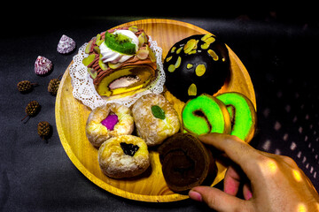 Indonesian sweet cakes served on natural wooden plate and spoon with black background highlighting traditional dessert texture and authentic tropical food style