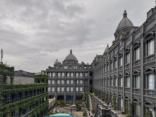 Bandung, Indonesia-December 14, 2025: Grand architectural view of GH Universal Hotel in Bandung, featuring classical grey facades, domes, lush greenery, and an inviting courtyard under a cloudy sky.