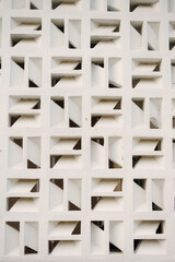 Geometric white facade with repeating square patterns, creating shadows and architectural interest