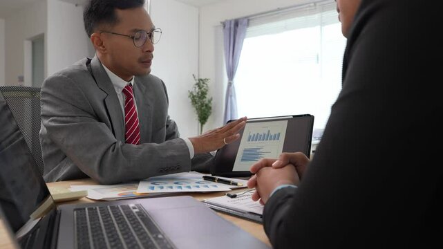 Financial advisory services Asian advisor showing investment plans to clients Professional team analyzing financial charts Discussing performance indicators