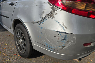 Rear-end collision damage on silver car with visible scrapes and paint transfer