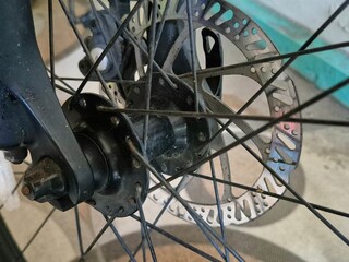 Close-up of bicycle disc brake system with black spokes and metal rotor on front wheel