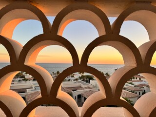 Sunset view of San Lucas del Cabo coast through white architectural fence