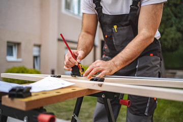 Unrecognizable men measuring wooden plank outdoors
