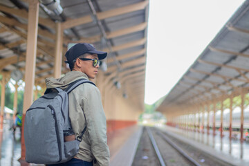 Young man standing alone at sunrise, standing on train station platform, holding map, confused but inspired, travel, direction, exploration, journey, freedom, lifestyle, waiting, seriousness, sunlight