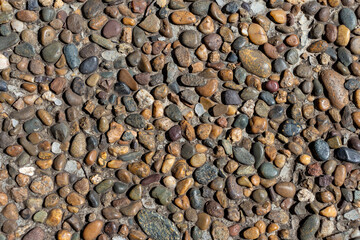 A close-up view of a diverse assortment of small stones and pebbles creating a textured, abstract background. The earthy tones and shapes provide a calm and inviting atmosphere.