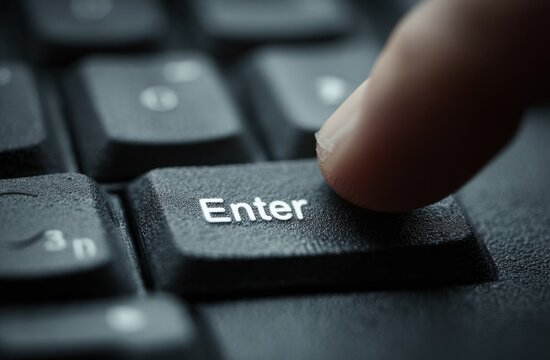 Fingertip poised above an enter key, ready to submit data into a digital world.