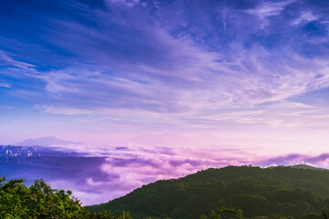 Fototapeta premium Description: A serene morning unfolds over the mountains of Shulin District New Taipei City Taiwan, with a soft pink and purple sky above a blanket of rolling clouds and distant city silhouettes.
