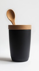 A beautiful wooden spoon and a stylish black tumbler placed on a soft beige surface accompanied by delicate dried flowers creating a cozy and inviting atmosphere for any kitchen setting
