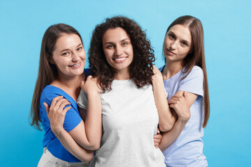 Three friends hugging on light blue background