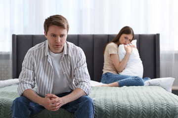 Woman and man having quarrel on bed at home, selective focus