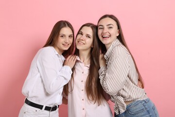 Friends hugging each other on pink background
