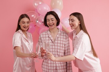 Pajama party. Happy friends with balloons clinking glasses on pink background