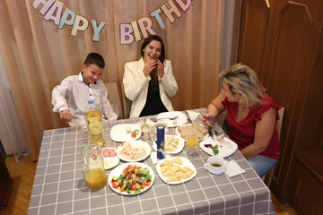 Celebrating a boy's birthday, the family sits at the table, drinks and treats. Birthday...