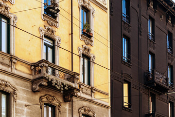 Milan, Italy - March 19, 2025: Black facade hotel and historic buildings with tram wires near...