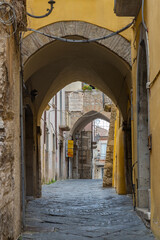 Narrow cobblestone alley passing under arches in Benevento, Italy