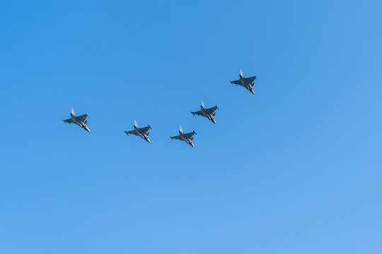 Gray fighter jets flying in formation in the blue sky