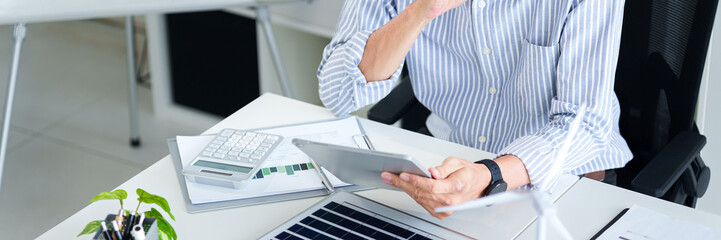 Asian adult man calculating sustainable business growth ESG investment strategy using digital...