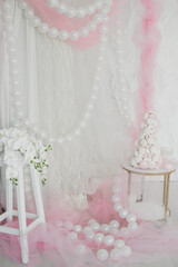 A cake made of marshmallows stands on a table in a pink studio or room decorated with balloons for a children's holiday celebration