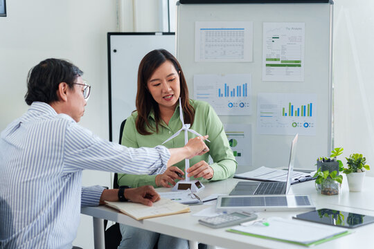 Asian business adults collaborate on renewable energy ESG initiatives sustainable development strategies and corporate responsibility in a modern office