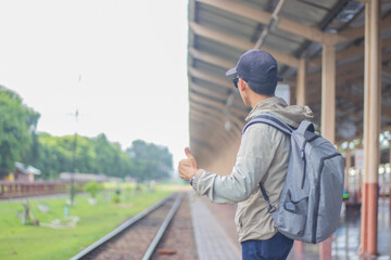 Young man standing alone at sunrise, standing on train station platform, holding map, confused but...