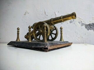 Antique brass artillery cannon still life on a distressed white table with grunge texture...