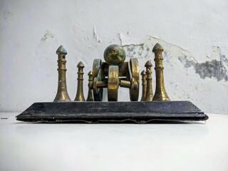Antique brass artillery cannon still life on a distressed white table with grunge texture background. Back View.
