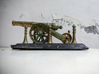 Antique brass artillery cannon still life on a distressed white table with grunge texture...