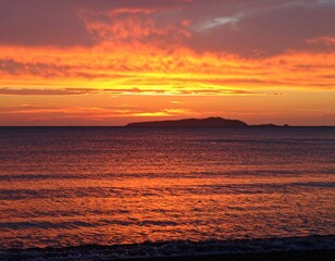 Dramatic sunset over ocean with a distant island silhouette