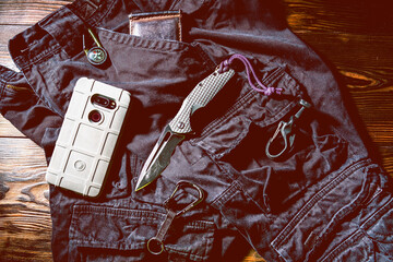 Folding knife for everyday wear. Knife and everyday items. Men's accessories on pants. Wallet and smartphone on pants.