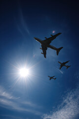 Silhouettes of various airplanes flying high in a clear blue sky, ultrabright background, showcasing the elegance and design of aircraft in flight.