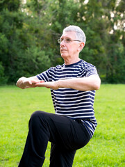 Mature retired wearing glasses plays sports in a city park during routine workout in morning. Staying active after retirement.