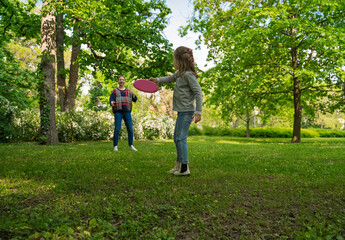 Cute little 5 year old girl playing frisbee with her mom in the park 